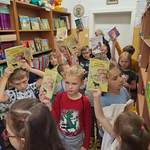 Dzieci w bibliotece szkolnej z książkami trzymającymi w górze.jpg